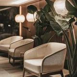 Lounge with rattan armchairs, paper lanterns and large plants against a wooden wall